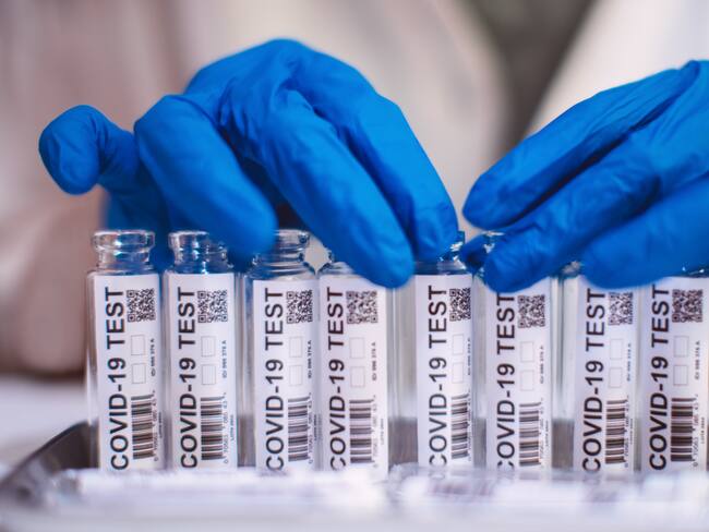 Doctor in protection gloves examining & organising test kit for COVID-19 in laboratory.