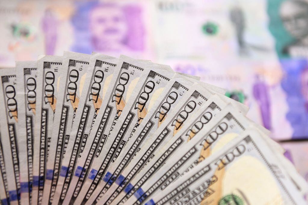 Dinero colombiano y dólares, imagen de referencia. (Photo by DANIEL MUNOZ/AFP via Getty Images)