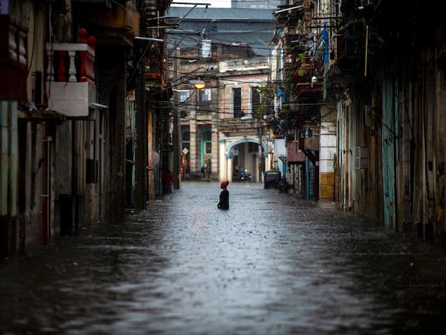 A woman wades along a flooded street of Havana, on June 3, 2022. - The remnant of Hurricane Agatha is causing intense and persistent rains this Friday in the western and central provinces of Cuba. (Photo by YAMIL LAGE / AFP) (Photo by YAMIL LAGE/AFP via Getty Images)