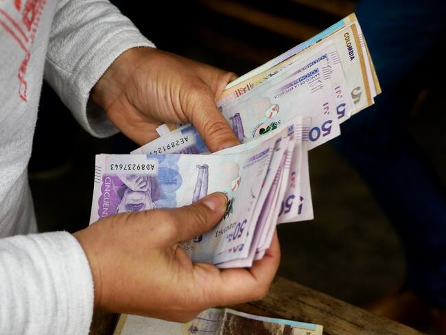 Imagen de referencia de persona contando billetes. Foto: Getty Images.