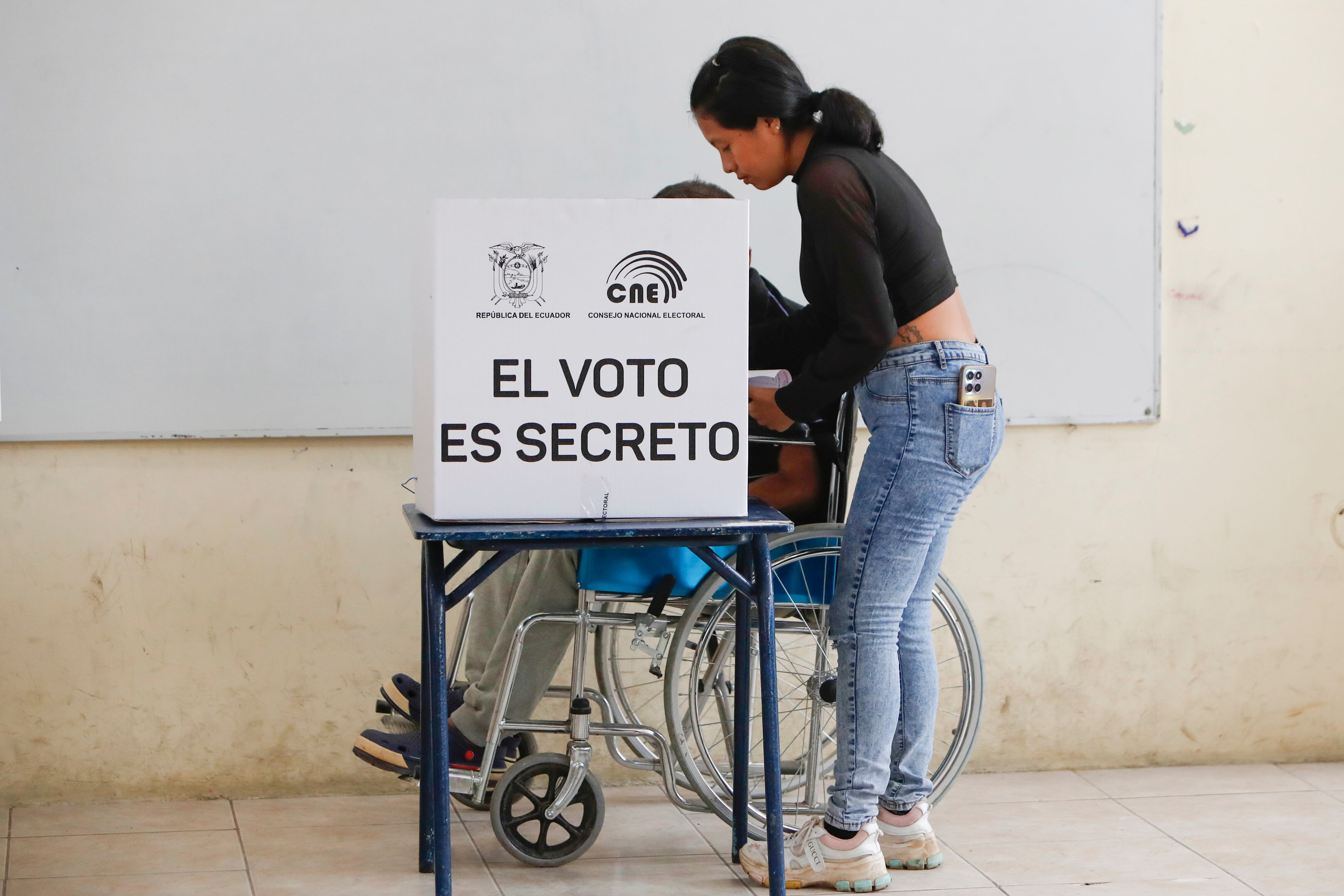 ACOMPAÑA CRÓNICA: ECUADOR ELECCIONES AMDEP5413. OLÓN (ECUADOR), 13/04/2025.- Un hombre en silla de ruedas marca su voto en un centro de votación este domingo, en Olón (Ecuador). En plena celebración del Domingo de Ramos, Ecuador elige a su presidente o presidenta para el período 2025-2029, en unos comicios marcados por una nueva declaratoria de estado de excepción, y la "ley seca", que restringe el consumo de bebidas alcohólicas, además de una inédita prohibición de votar con teléfono en mano. EFE/ Carlos Durán Araújo