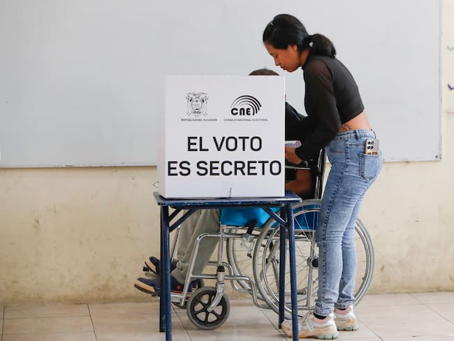 ACOMPAÑA CRÓNICA: ECUADOR ELECCIONES AMDEP5413. OLÓN (ECUADOR), 13/04/2025.- Un hombre en silla de ruedas marca su voto en un centro de votación este domingo, en Olón (Ecuador). En plena celebración del Domingo de Ramos, Ecuador elige a su presidente o presidenta para el período 2025-2029, en unos comicios marcados por una nueva declaratoria de estado de excepción, y la "ley seca", que restringe el consumo de bebidas alcohólicas, además de una inédita prohibición de votar con teléfono en mano. EFE/ Carlos Durán Araújo