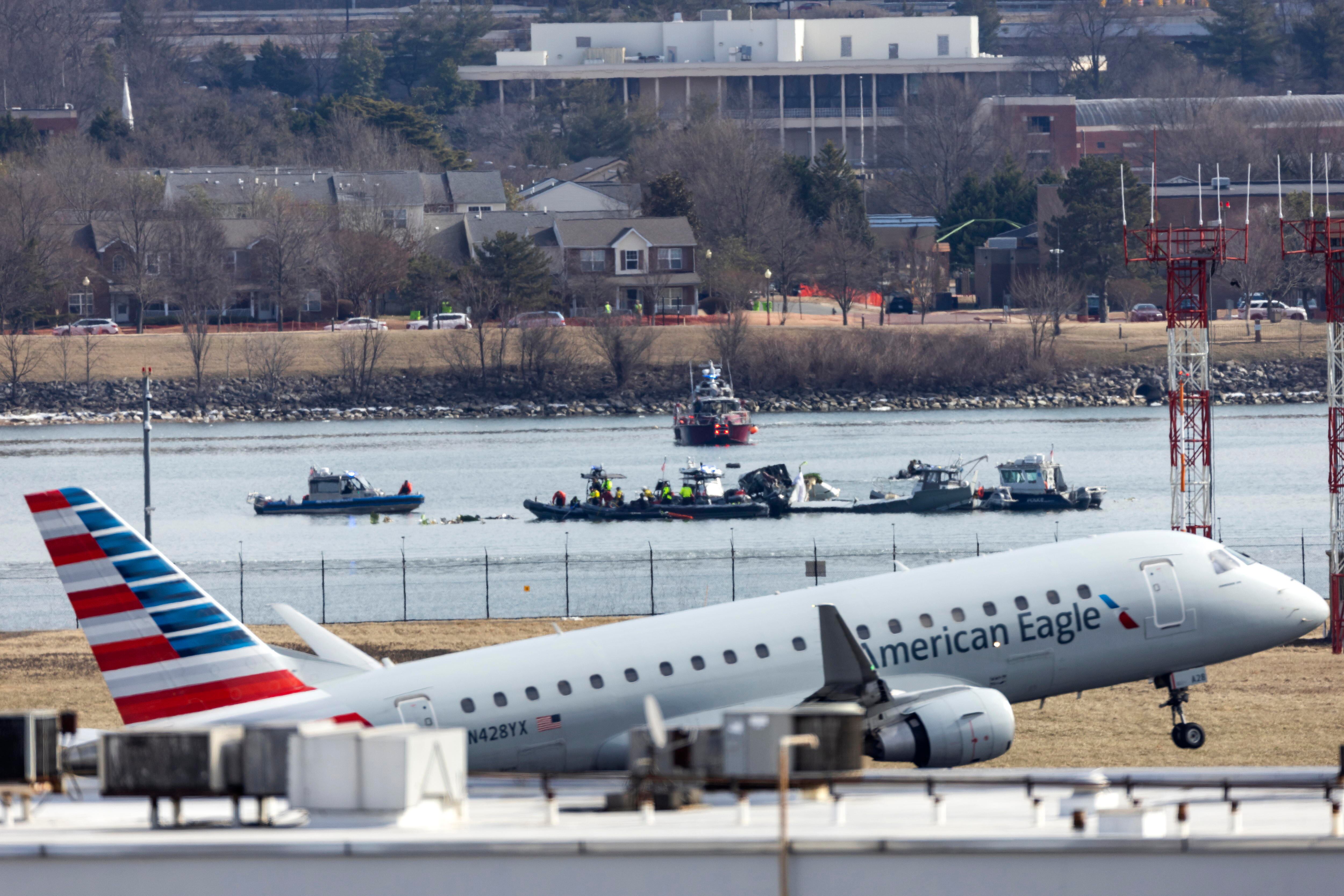 Washington (Estados Unidos), 30/01/2025.- Un vuelo de American Eagle despega del Aeropuerto Nacional Ronald Reagan de Washington frente a los restos de un avión comercial que colisionó con un helicóptero militar.