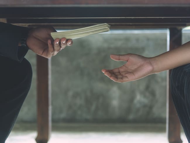 Foto de referencia de una persona entregando dinero a otra. Foto: Getty Images