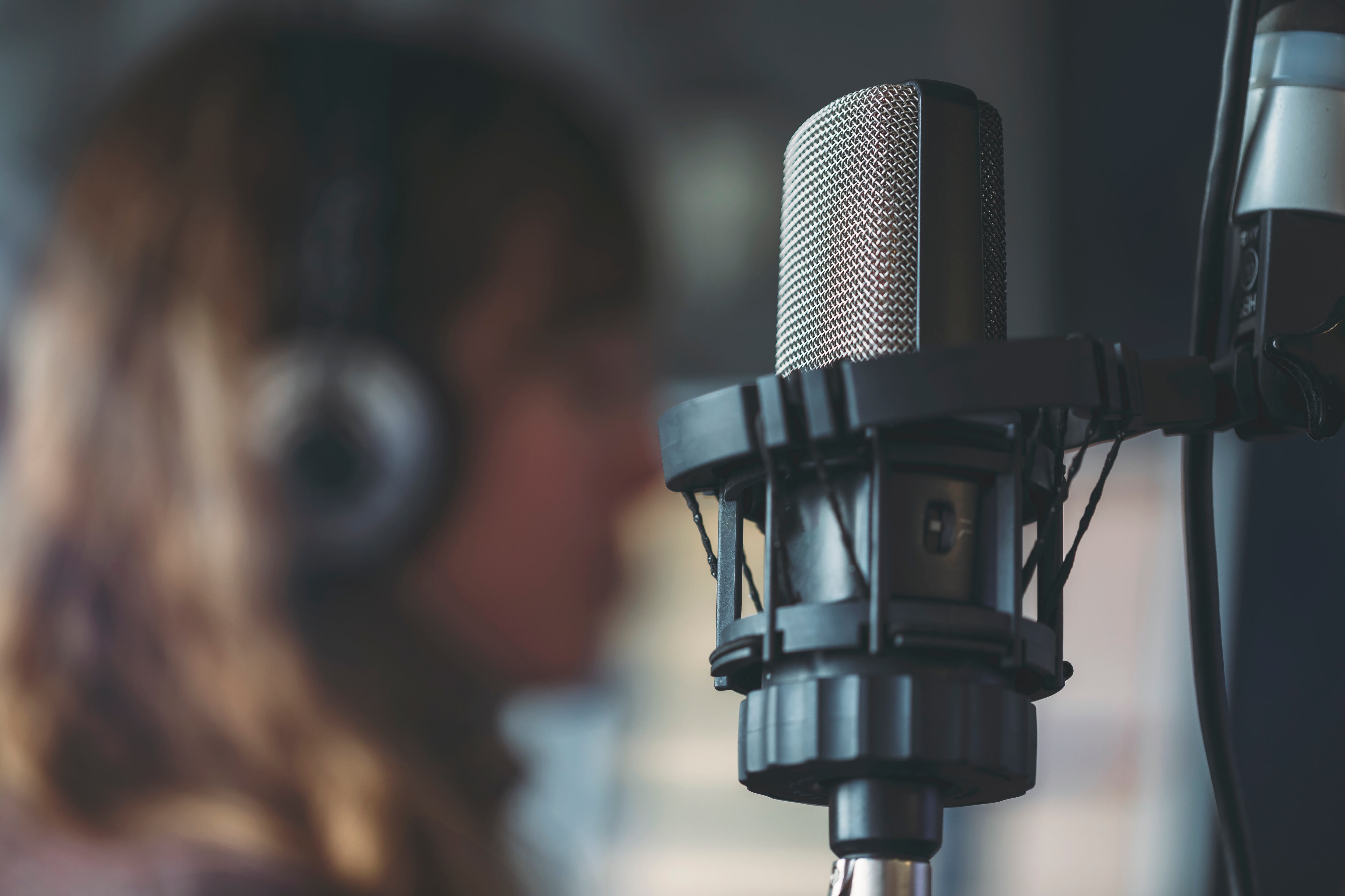 Close up of microphone in radio broadcast studio and female radio host on the background