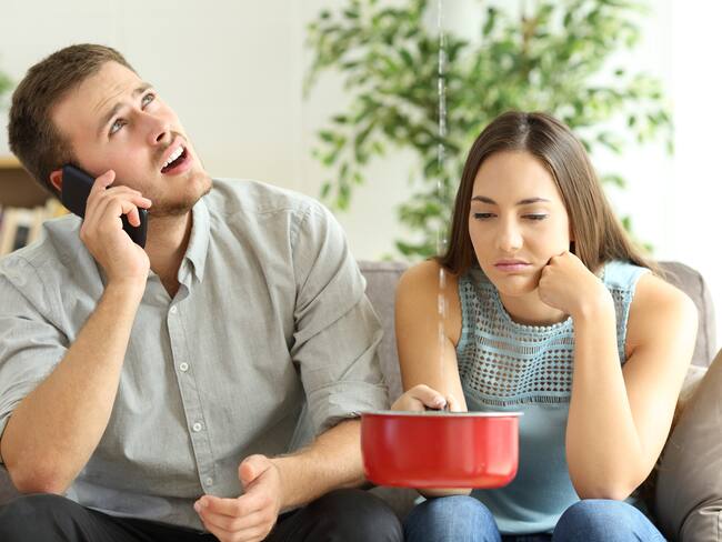 Mujer frustrada porque en su vivienda arrendada hay goteras, mientras su pareja llama a quejarse por el daño (Getty Images)