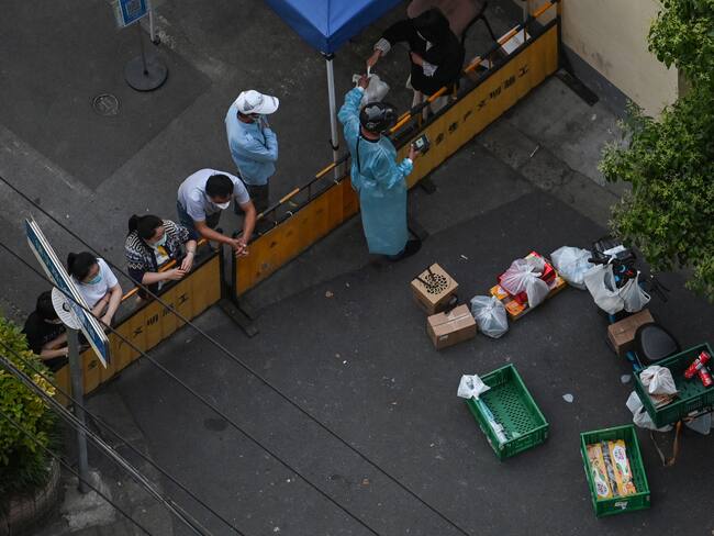 A resident collects food from a delivery worker at a checkpoint on a street during a Covid-19 coronavirus lockdown in the Jing'an district in Shanghai on May 17, 2022. (Photo by Hector RETAMAL / AFP) (Photo by HECTOR RETAMAL/AFP via Getty Images)
