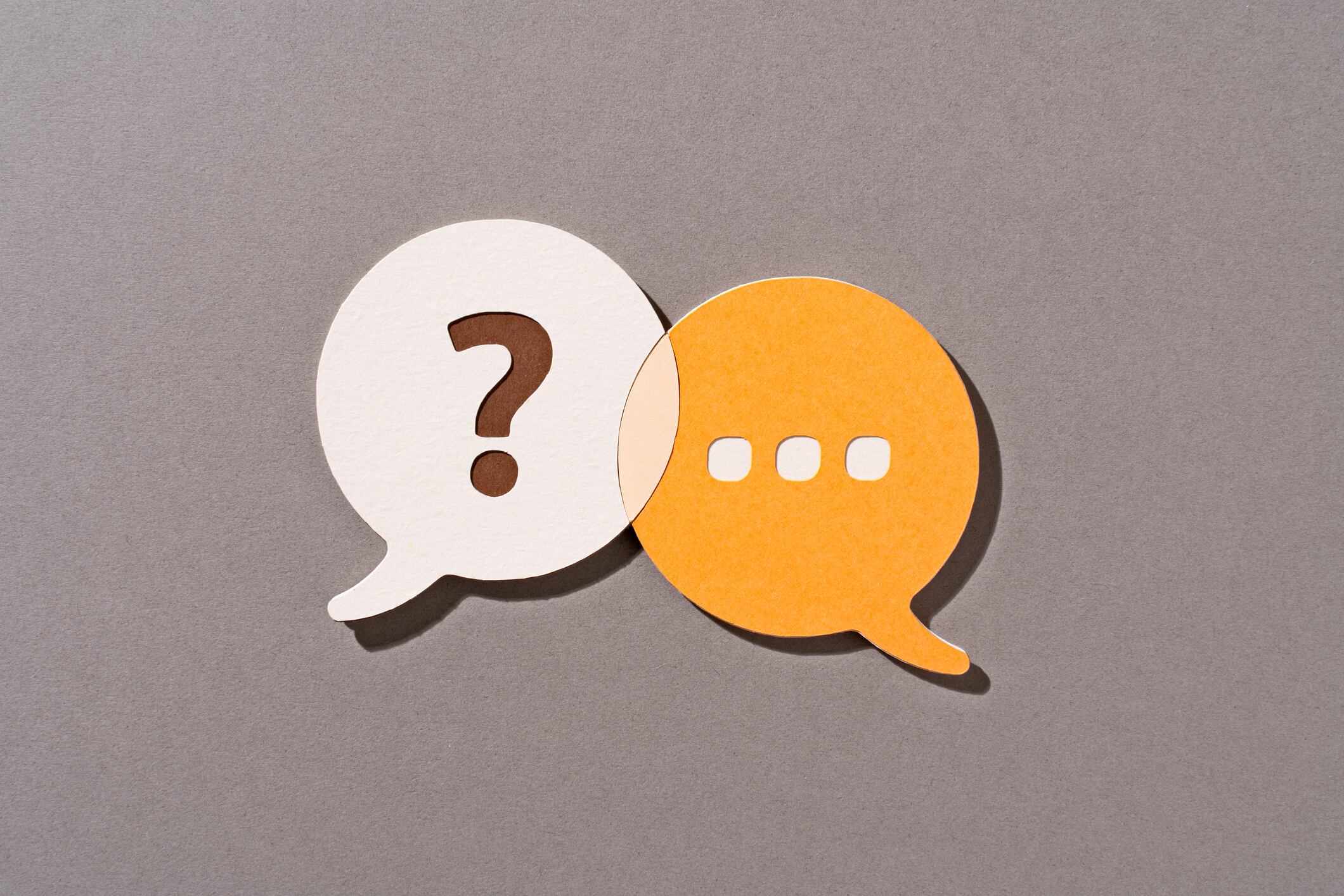 Paper Craft of Orange Color Question and Answer Speech Bubbles Overlapping on Brown Background Front View.