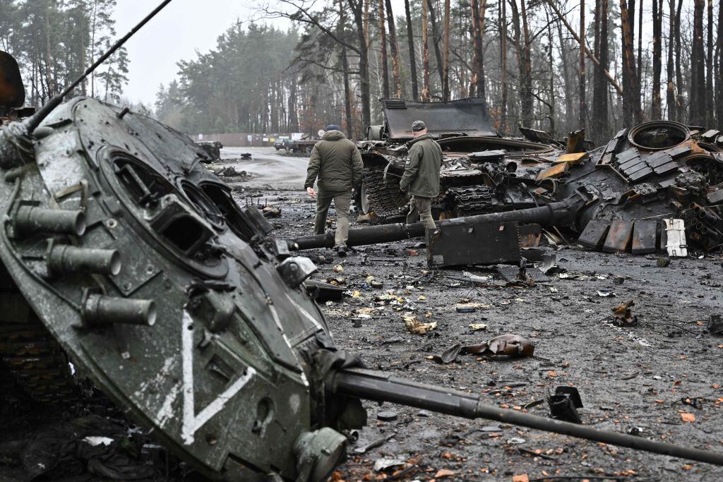 Militares ucranianos caminan junto a tanques destruidos (Photo by Genya SAVILOV / AFP) (Photo by GENYA SAVILOV/AFP via Getty Images)