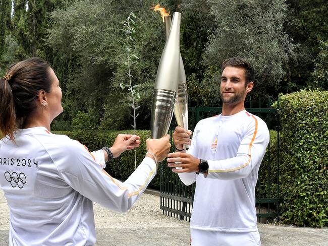 Ancient Olympia (Greece), 16/04/2024.- First torchbearer Greek Rowing Olympic Champion Stefanos Ntouskos (R), passes the Olympic Flame to the France Swimming Olympic champion Laure Manaudou (L) during the Lighting Ceremony of the Olympic Flame for the Paris 2024 Olympic Games, in Archaia Olympia, Greece, 16 April 2024. The Summer Olympics Games will be held in Paris, France from 26 July to 11 August 2024. (Francia, Grecia) EFE/EPA/VASSILIS PSOMAS