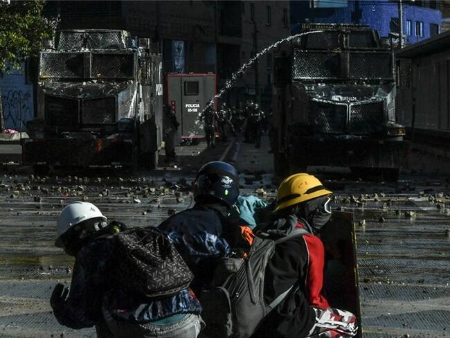 Manifestantes en Colombia enfrentándose a dos tanquetas del Esmad. Foto: JOAQUIN SARMIENTO/AFP via Getty Images