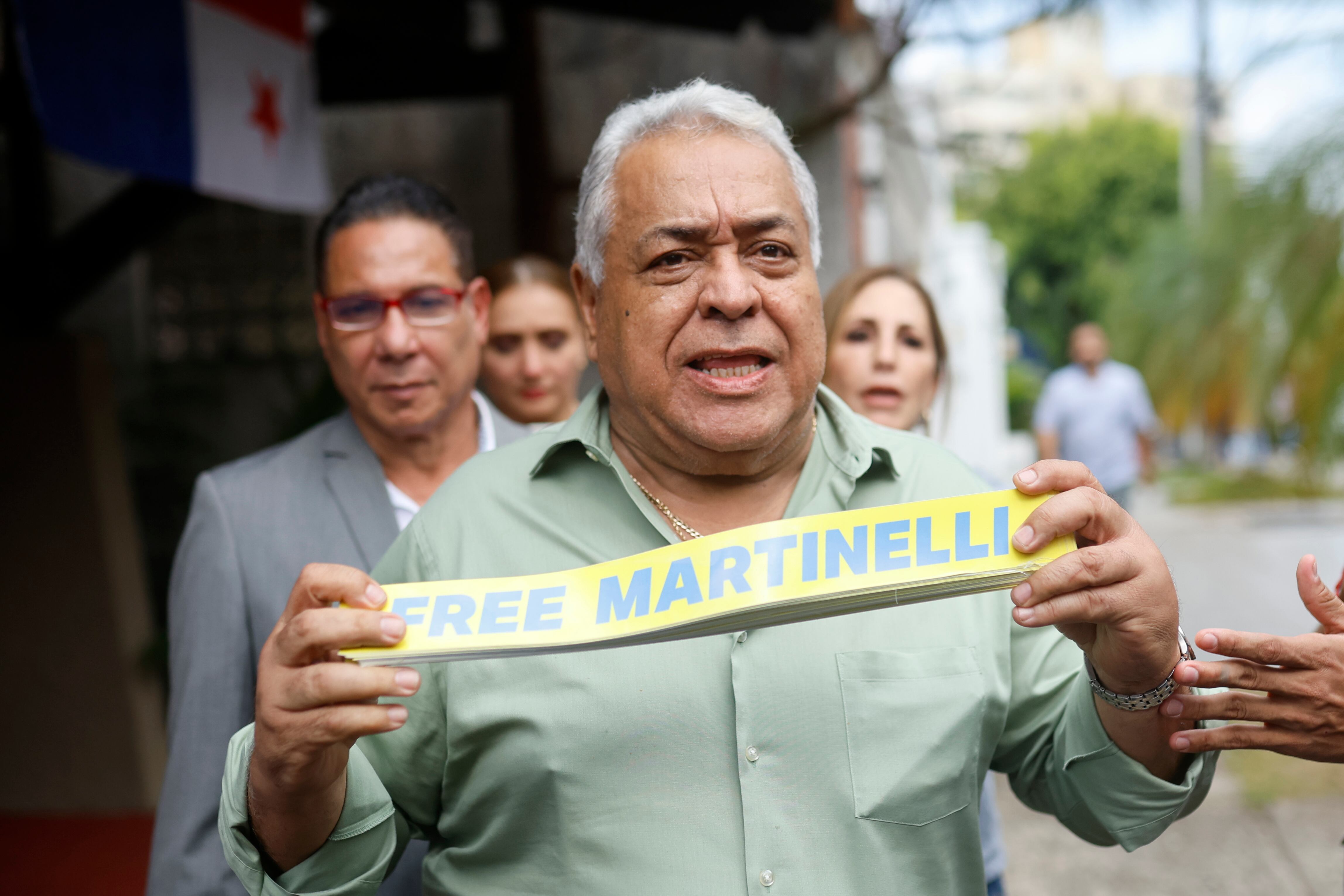 AME3200. CIUDAD DE PANAMÁ (PANAMÁ), 27/03/2025.- El abogado del expresidente panameño Ricardo Martinelli, Alejandro Pérez, sostiene carteles este jueves, en Ciudad de Panamá (Panamá). El Gobierno de Panamá otorgó el salvoconducto al expresidente Martinelli, asilado desde el 7 de febrero de 2024 en la Embajada nicaragüense tras ser condenado a más de 10 años de cárcel por blanqueo, para que pueda viajar a Nicaragua y le ha dado plazo para ello hasta el 31 de marzo. EFE/ Bienvenido Velasco