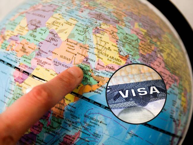De fondo, una persona señalando un país en un globo terráqueo. En el círculo, la imagen de la visa de turista para viajar a Estados Unidos / Fotos: GettyImages