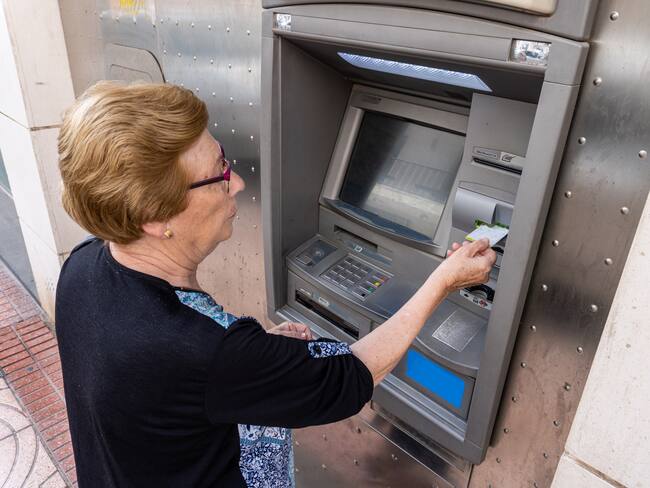Mujer anciana retirando dinero de un cajero electrónico (Foto vía Getty Images)