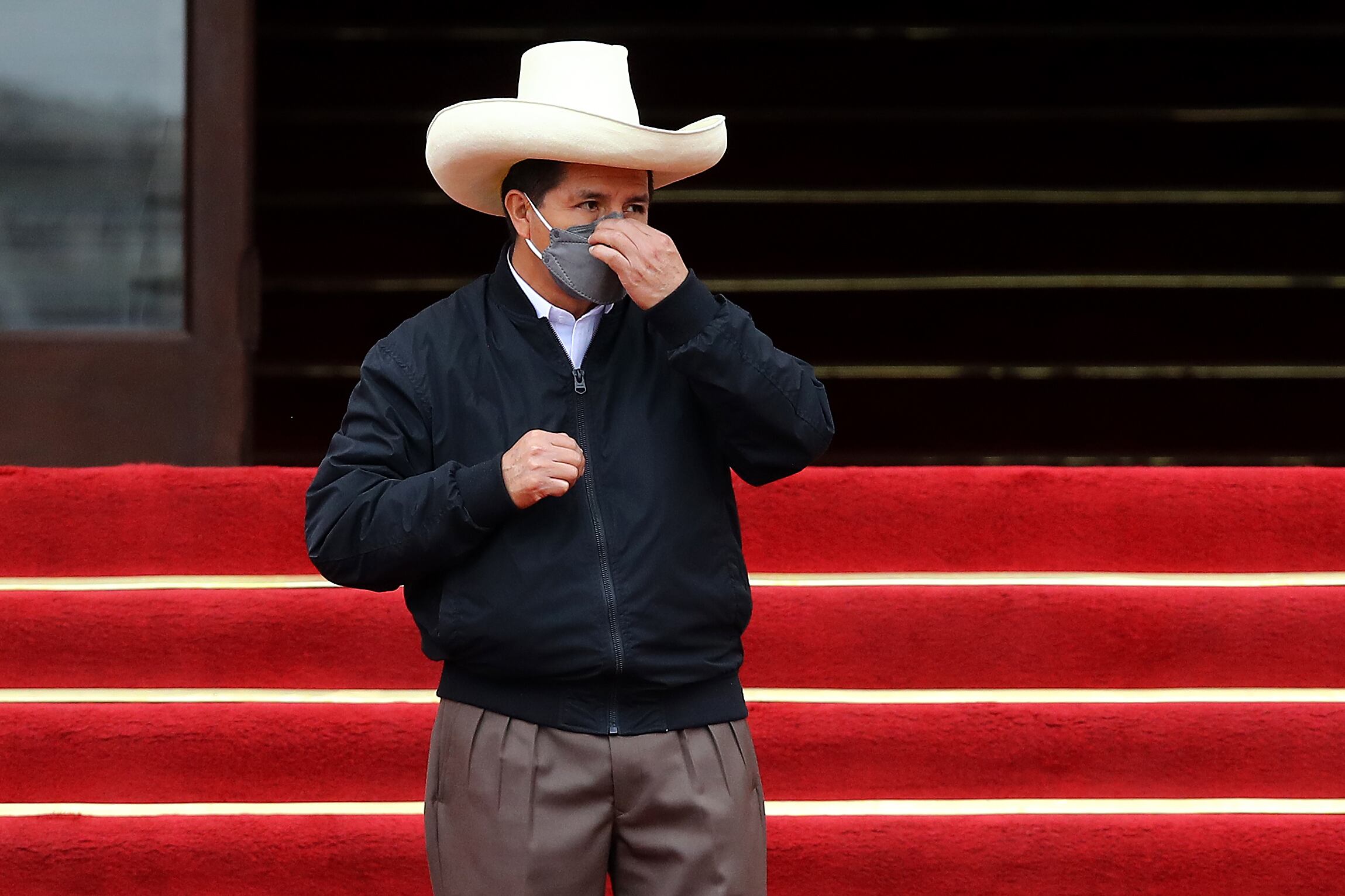 LIMA, PERU - DECEMBER 05: Peruvian President Pedro Castillo (L) puts his mask on after his speech during an event to deliver firetrucks to Volunteer firefighters of Peru on December 5, 2021 in Lima, Peru. After only four months in power, National Congress will vote this week on whether to start the formal impeachment process to Castillo. The Left-wing President will also be questioned by prosecutors on December 14th over promotions for military officers. (Photo by Leonardo Fernandez/Getty Images)