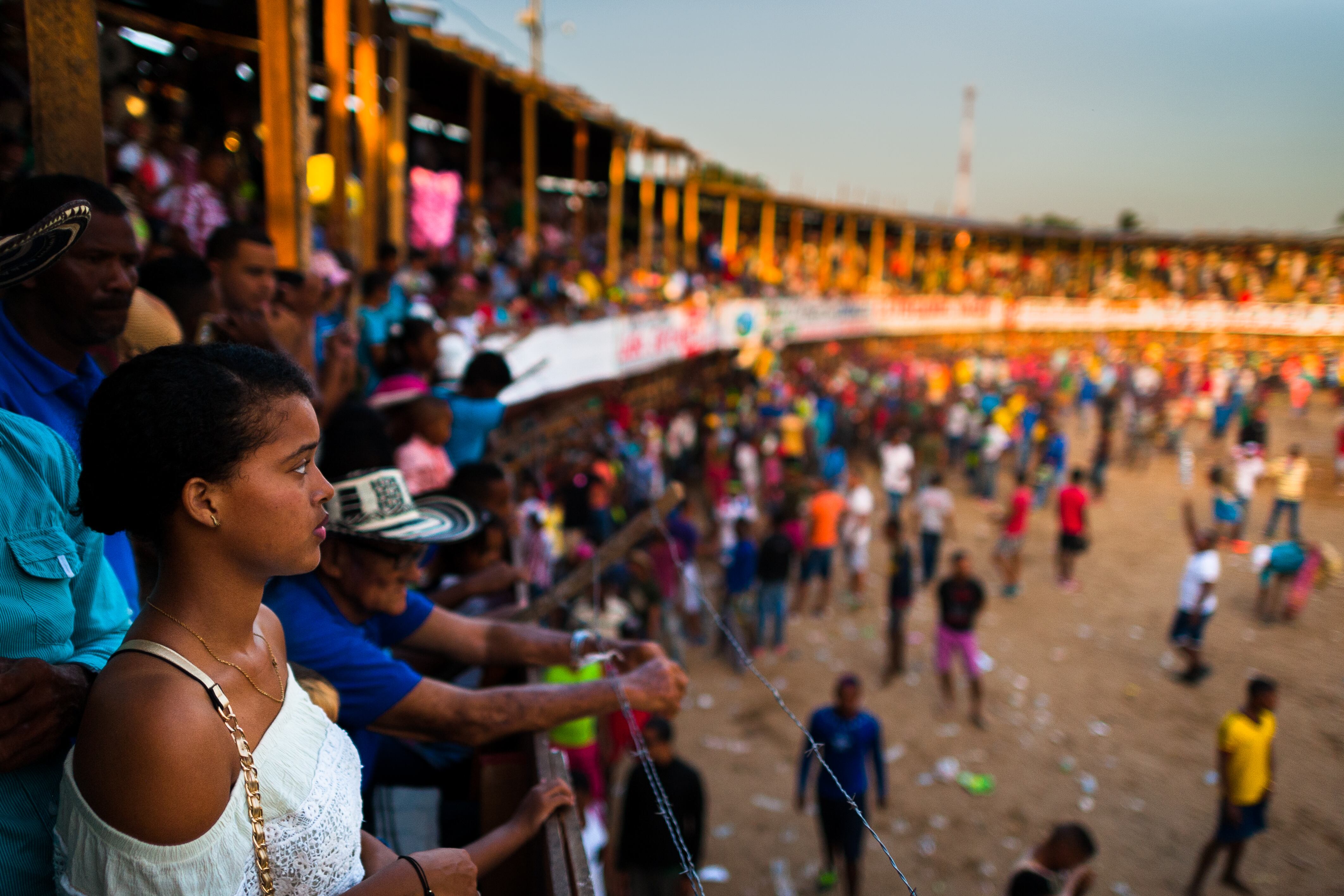 SOPLAVIENTO, COLOMBIA - DECEMBER 17: A young Colombian woman looks down at the amateur bullfighters in the arena of a 'Corraleja' bullfighting festival on December 17, 2017 in Soplaviento, Colombia. Amateur bullfights known as 'Corralejas' take place in villages and towns on the Caribbean coast of Colombia. Families and people from all around meet on wooden bleachers of a temporarily built bullring to eat, drink and watch hundreds of amateur bullfighters risking their lives, taunting bulls, and showing their masculinity and courage in the arena. Unlike the corrida, the bulls in 'Corralejas' are never killed. (Photo by Jan Sochor/Getty Images)