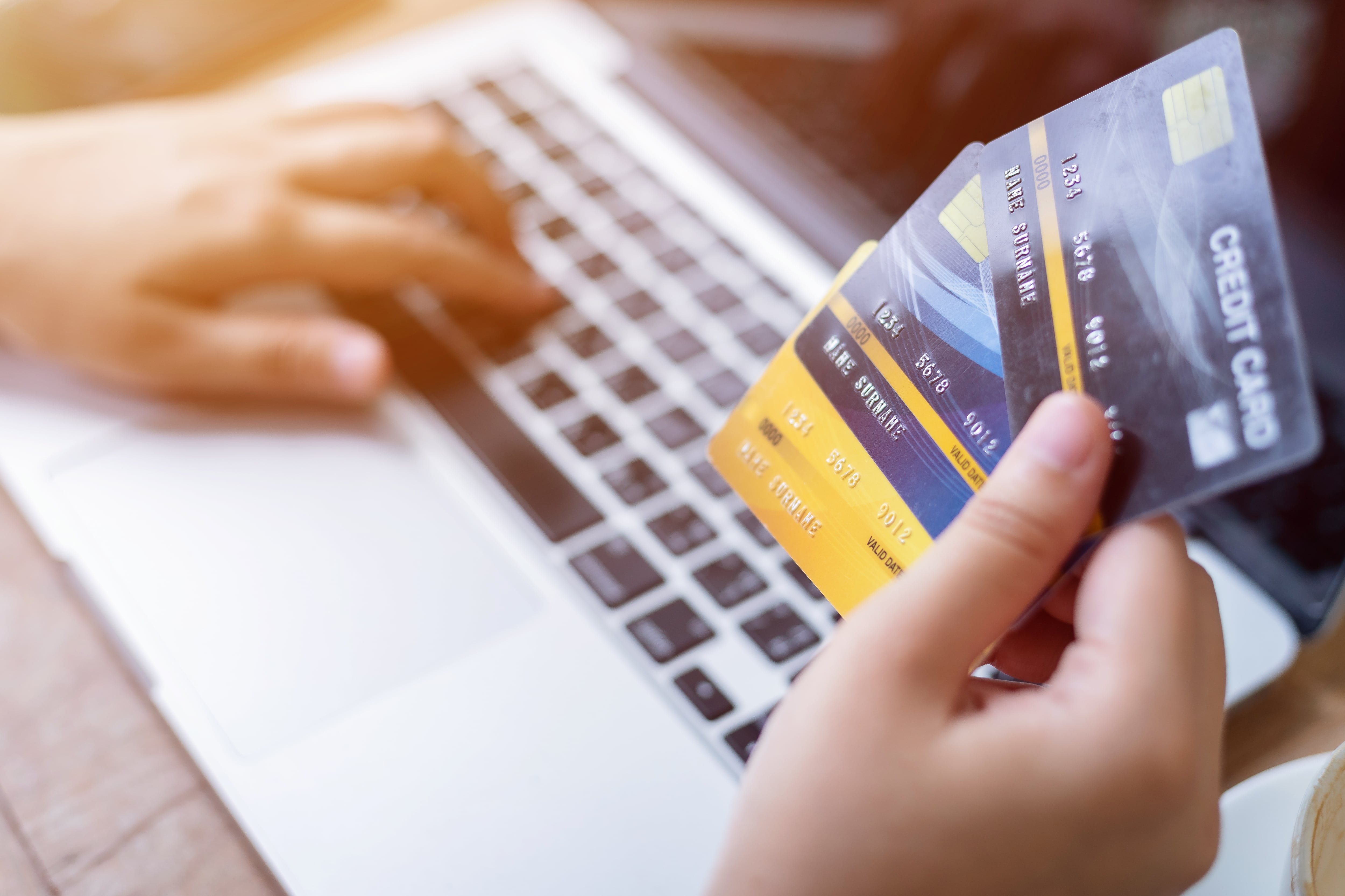 Persona con tres tarjetas de crédito y un computador. Foto: Getty Images.
