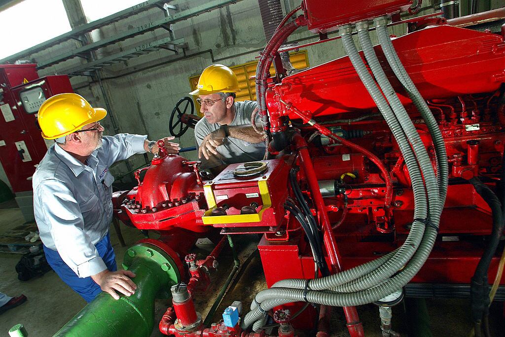 Dos trabajadores discuten el 1 de octubre de 2003 la mecánica del potente motor ubicado en la sala de máquinas principal del centro de procesamiento de carbón de Pego, cerca de Lisboa, Portugal.