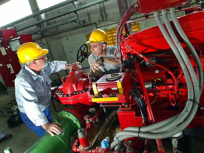 Dos trabajadores discuten el 1 de octubre de 2003 la mecánica del potente motor ubicado en la sala de máquinas principal del centro de procesamiento de carbón de Pego, cerca de Lisboa, Portugal.