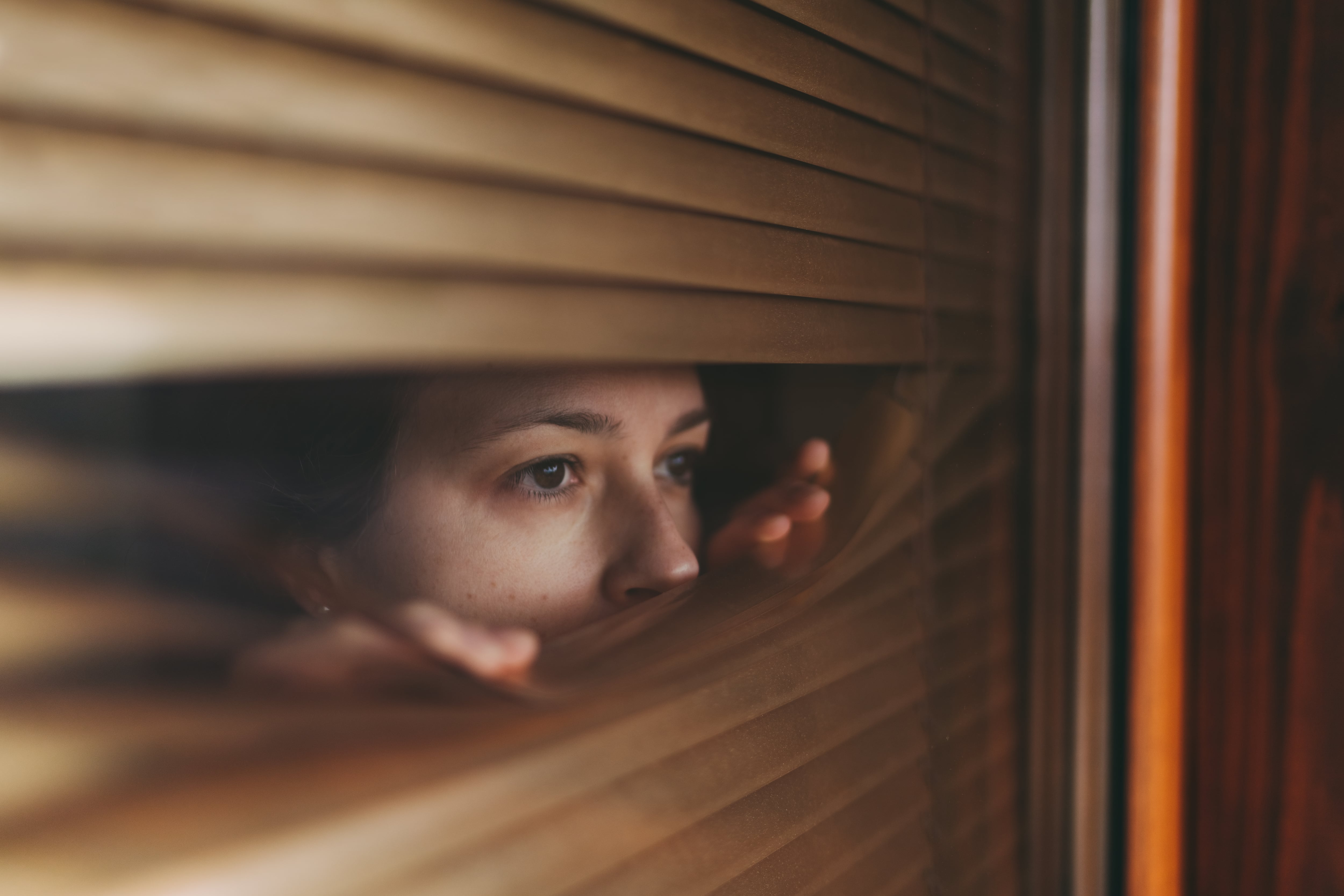 Woman at home during COVID-19 pandemic is looking through window