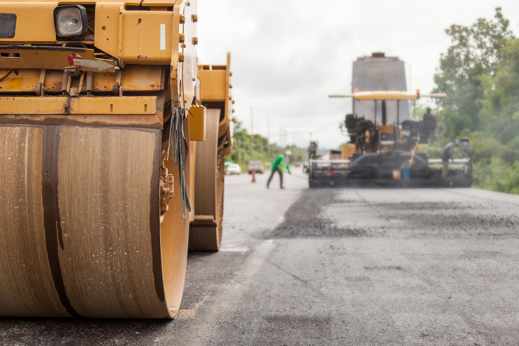 Road construction works with roller compactor machine and asphalt finisher.