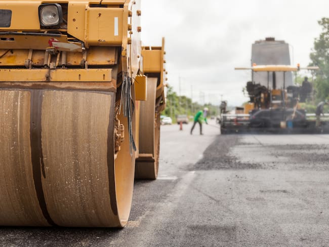 Road construction works with roller compactor machine and asphalt finisher.