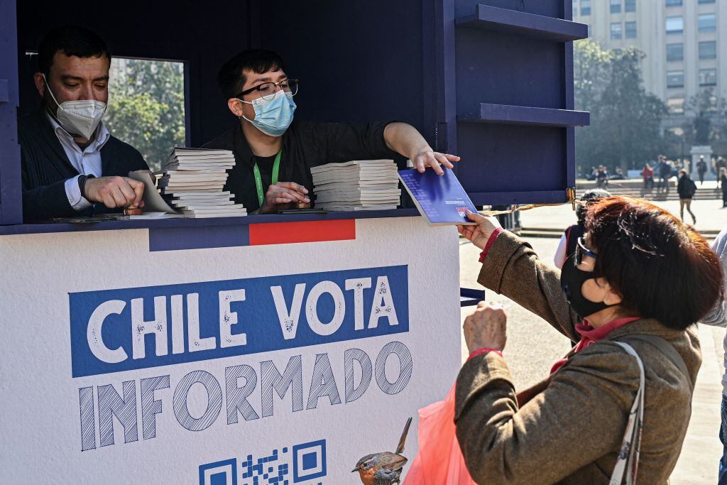 A woman receives a copy of the draft of Chile's new constitution in front La Moneda presidential palace in Santiago, on August 11, 2022. - Chile votes on September 4 in a plebiscite if to approve or reject the draft of the new constitution. Chile's constitutional convention, made up of 154 members who are mostly political independents, spent a year creating the new document to replace the constitution adopted during the Augusto Pinochet dictatorship (1973-1990). (Photo by Martin BERNETTI / AFP) (Photo by MARTIN BERNETTI/AFP via Getty Images)