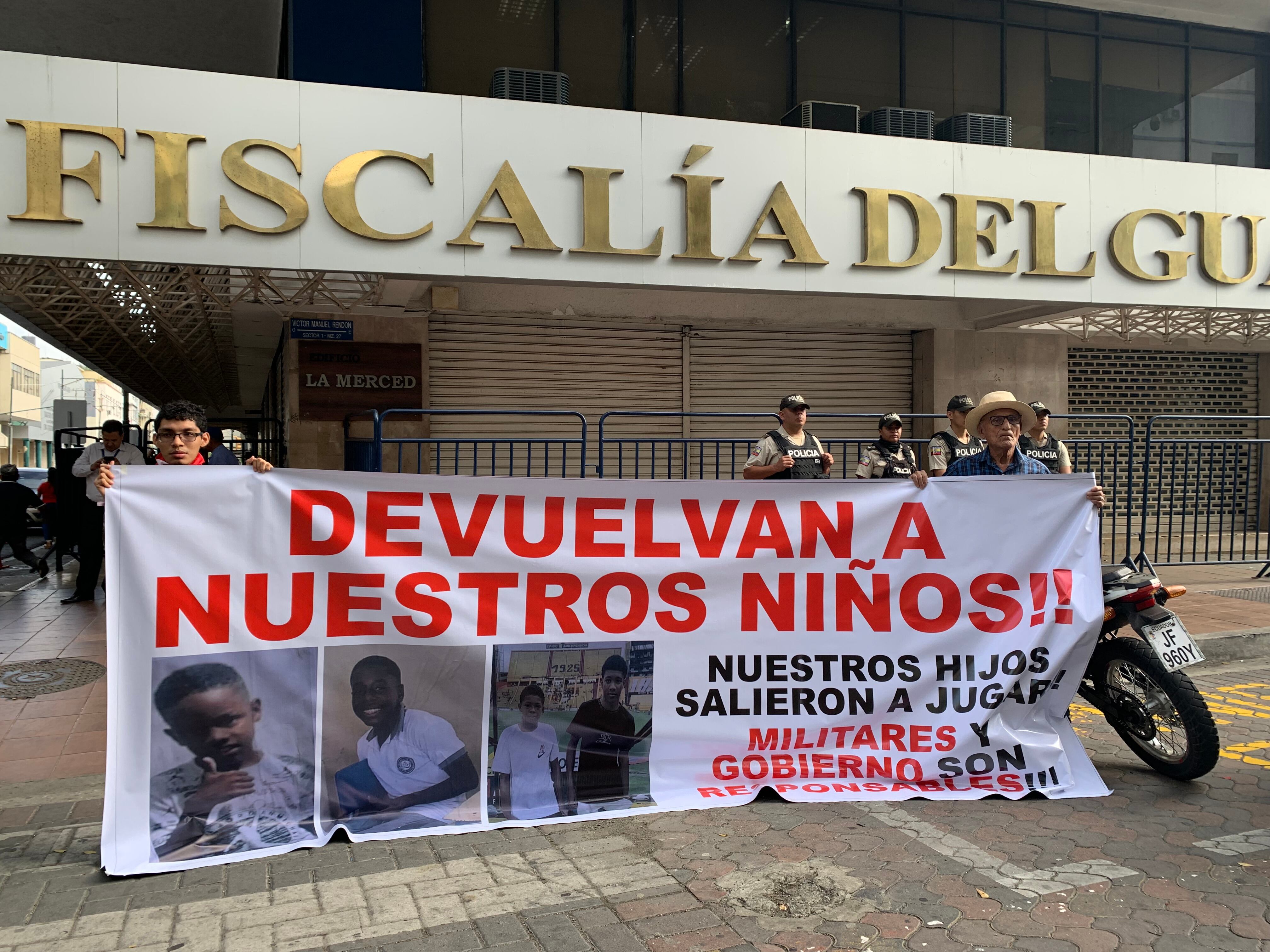 GUAYAQUIL (ECUADOR), 24/12/2024.- Dos personas sosteniendo un cartel en los exteriores de la Fiscalía Provincial del Guayas con el mensaje "devuelvan a nuestros niños", en alusión a los cuatro menores desaparecidos el 8 de diciembre.