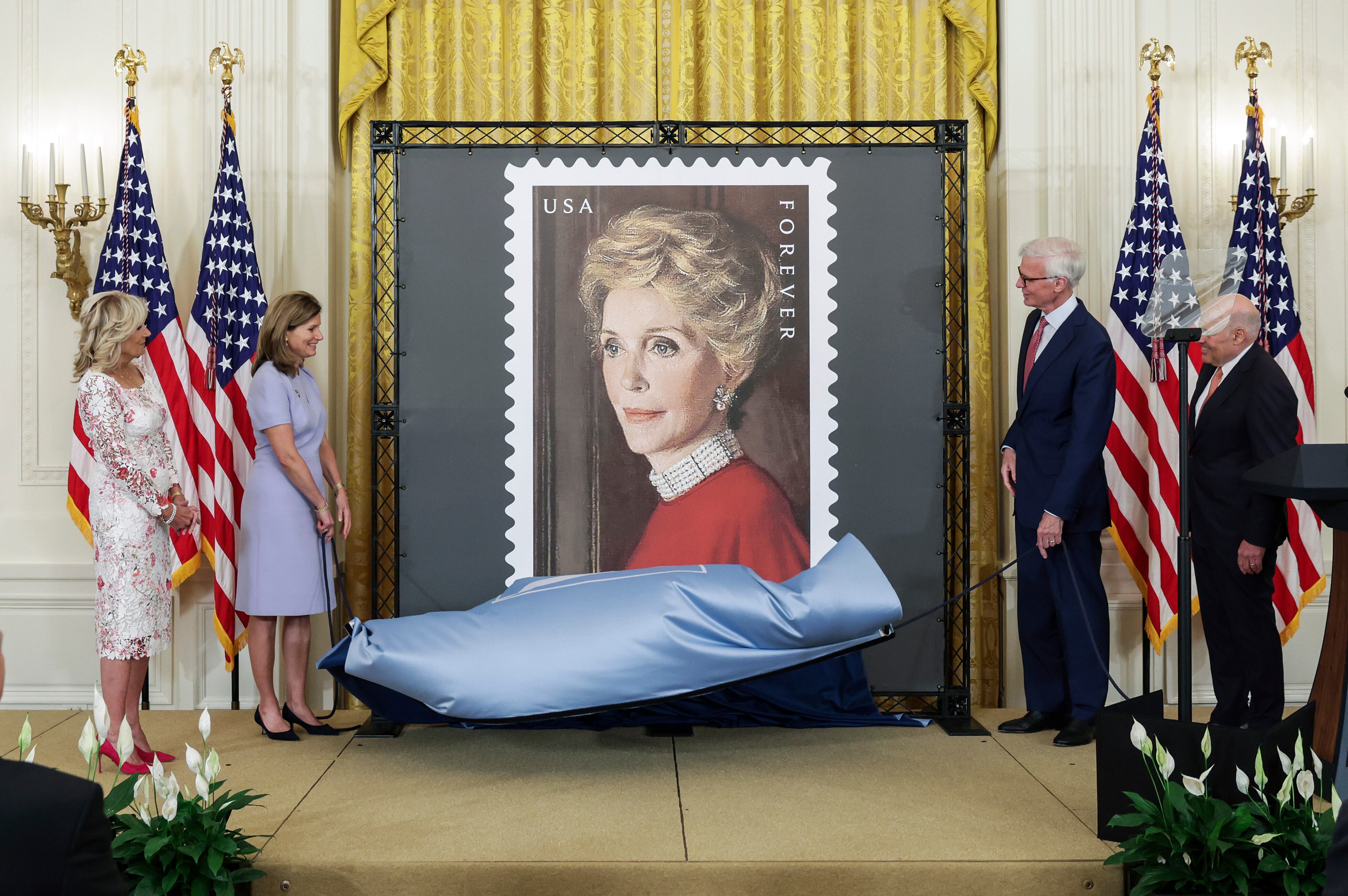 WASHINGTON, DC - JUNE 06: (L-R) First Lady Jill Biden, Anne Peterson, Nancy Reagan’s niece, Fred Ryan, Chairman of the Board of Trustees of The Ronald Reagan Presidential Foundation and Institute and Louis DeJoy, U.S. Postal Service Postmaster General, unveil the Nancy Regan stamp, in the East Room at the White House on June 06, 2022 in Washington, DC. The U.S. Postal Service unveiled the stamp honoring the legacy of First Lady Nancy Reagan and her role in helping to shape President Ronald Regan's Administration. (Photo by Kevin Dietsch/Getty Images)