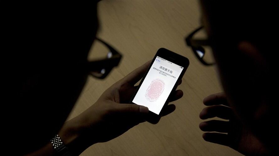 Un empleado de Apple le muestra a un periodista cómo funciona la tecnología detectora de huellas digitales en un iPhone 5S durante una presentación en Beijing . Foto: Associated Press - AP - Ng Han Guan
