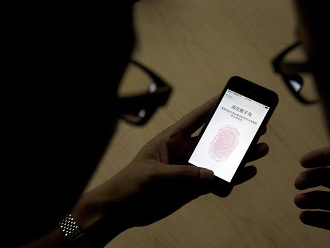 Un empleado de Apple le muestra a un periodista cómo funciona la tecnología detectora de huellas digitales en un iPhone 5S durante una presentación en Beijing . Foto: Associated Press - AP - Ng Han Guan
