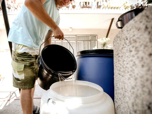 Imagen de referencia de persona con baldes de agua. Foto: Getty Images