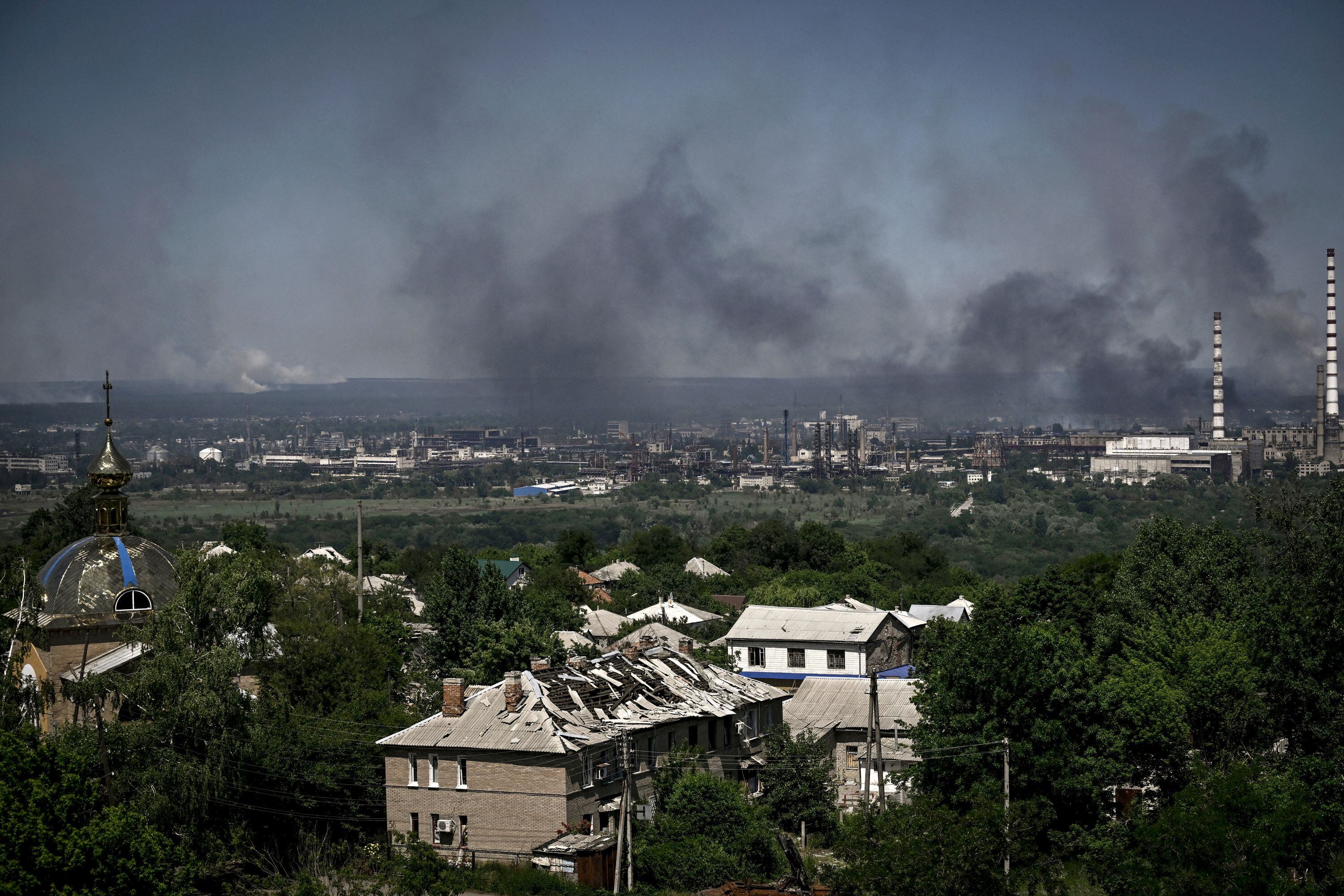A damaged building is pictured in Lysychansk as black smoke and dirt rise from the nearby city of Severodonetsk during battle between Russian and Ukrainian troops in the eastern Ukraine region of Donbas on June 9, 2022. (Photo by ARIS MESSINIS / AFP) (Photo by ARIS MESSINIS/AFP via Getty Images)