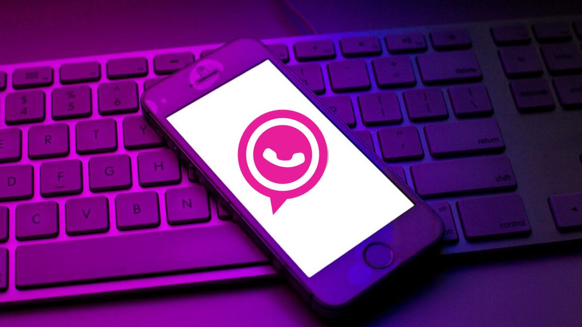 Celular iPhone con el logo de WhatsApp rosado en su pantalla, sobre un teclado de computador (Getty Images)