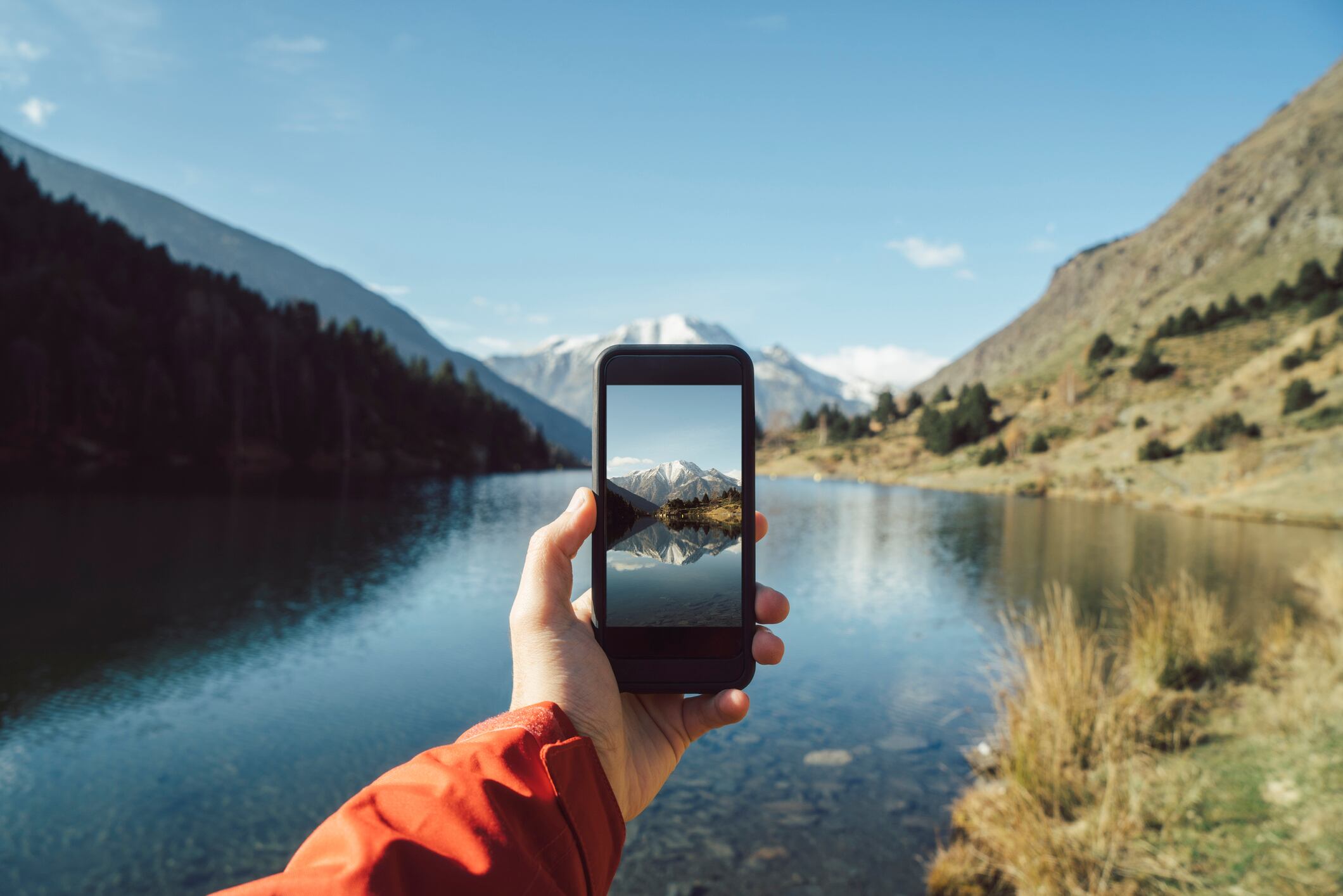 Hombre tomando foto del paisaje de montaña en Francia con su celular (Getty Images)