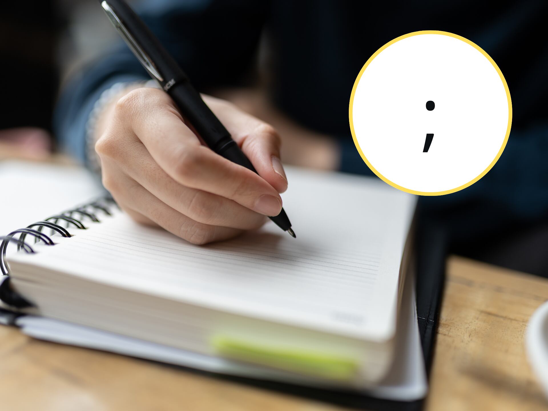 Persona escribiendo en un cuaderno, en el círculo el signo de punto y coma (GettyImages)
