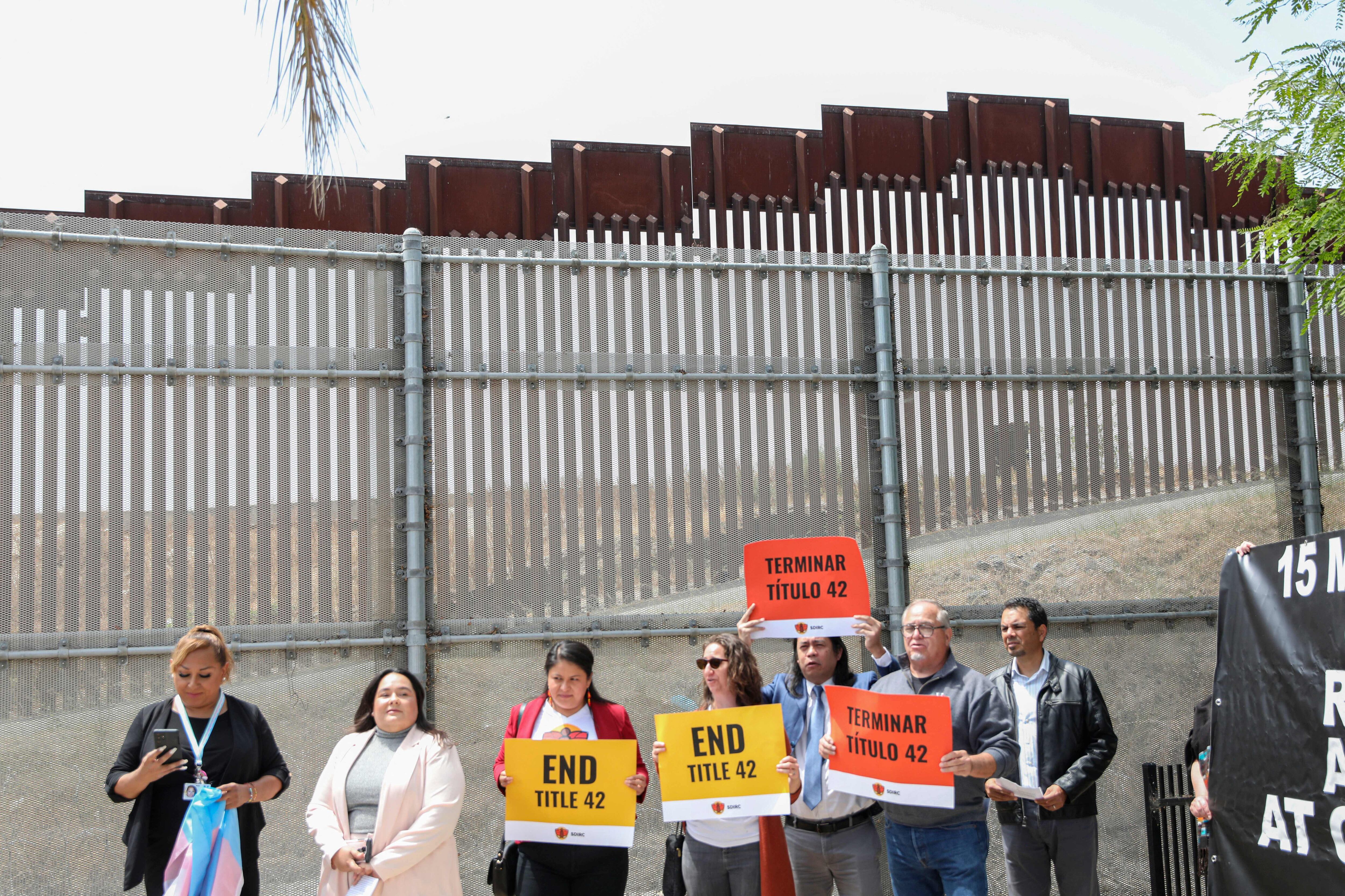 Immigration rights advocates stand at the US-Mexico border wall during a protest against Title 42 in San Ysidro, California, on May 23, 2022. - A health rule imposed at the start of the Covid-19 pandemic that has blocked most asylum seekers at the US border with Mexico must stay in place, a judge ruled Friday. Title 42, the colloquial name for an order that can effectively prevent anyone without a visa from entering the United States, even to claim asylum, was due to expire on Monday. (Photo by Sandy Huffaker / AFP) (Photo by SANDY HUFFAKER/AFP via Getty Images)
