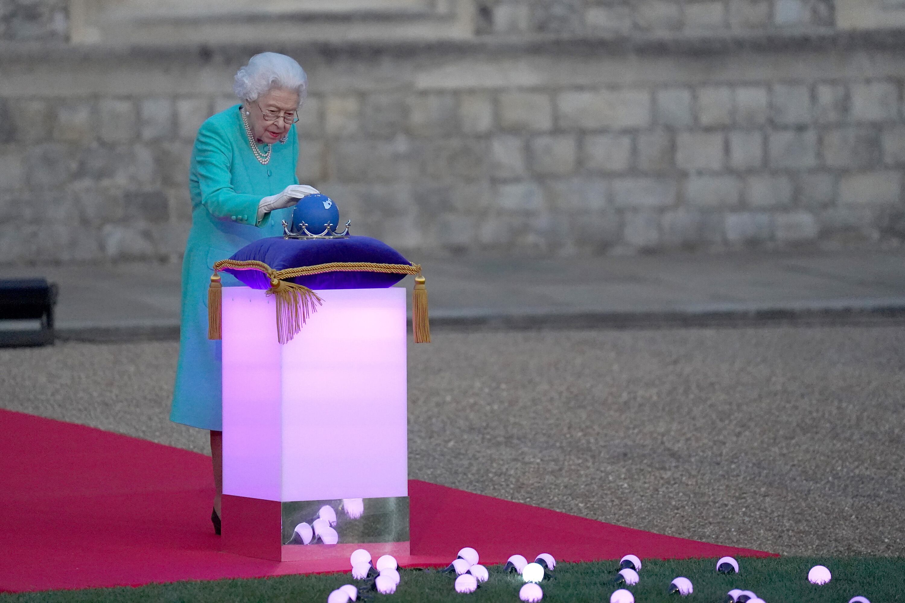 WINDSOR, ENGLAND - JUNE 02: Britain's Queen Elizabeth II touches the Commonwealth Nations Globe to start the lighting of the Principal Beacon outside of Buckingham Palace in London, from the Quadrangle at Windsor Castle in Windsor, west of London, as part of Platinum Jubilee celebrations on June 2, 2022 in Windsor, England. (Photo by  Steve Parsons-Pool/Getty Images)