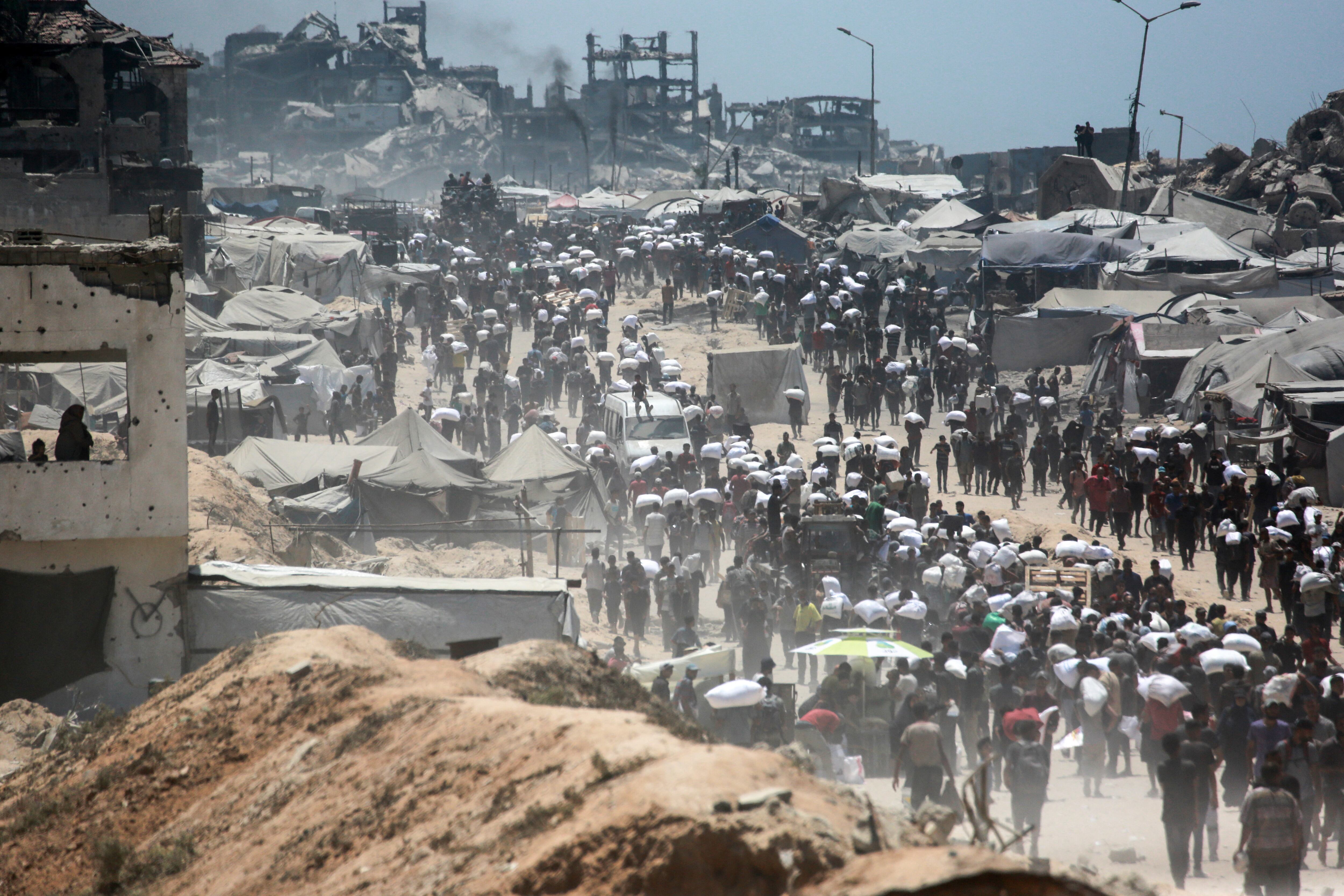 Palestinians carry bags of flour that they obtained from aid trucks which entered Gaza through the Zikim crossing point, in Jabalia in the northern Gaza Strip on August 1, 2025. The UN human rights office said on August 1 that 1,373 Palestinians have been killed while waiting for aid in the shortage-stricken Gaza Strip since late May, most of them by the Israeli military. (Photo by Bashar TALEB / AFP)
