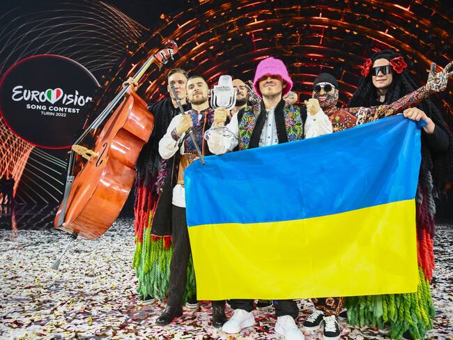 TOPSHOT - Members of the band "Kalush Orchestra" pose onstage with the winner's trophy and Ukraine's flags after winning on behalf of Ukraine the Eurovision Song contest 2022 on May 14, 2022 at the Pala Alpitour venue in Turin. (Photo by Marco BERTORELLO / AFP) (Photo by MARCO BERTORELLO/AFP via Getty Images)