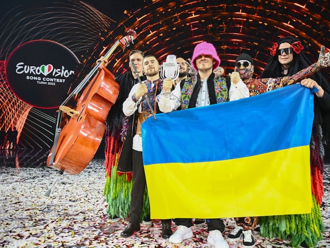 TOPSHOT - Members of the band &quot;Kalush Orchestra&quot; pose onstage with the winner&#039;s trophy and Ukraine&#039;s flags after winning on behalf of Ukraine the Eurovision Song contest 2022 on May 14, 2022 at the Pala Alpitour venue in Turin. (Photo by Marco BERTORELLO / AFP) (Photo by MARCO BERTORELLO/AFP via Getty Images)