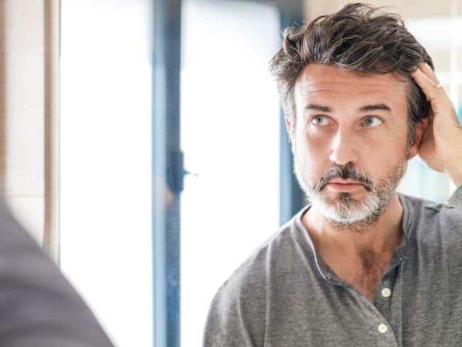 Hombre revisa sus canas en un espejo, imagen de referencia - Getty Images