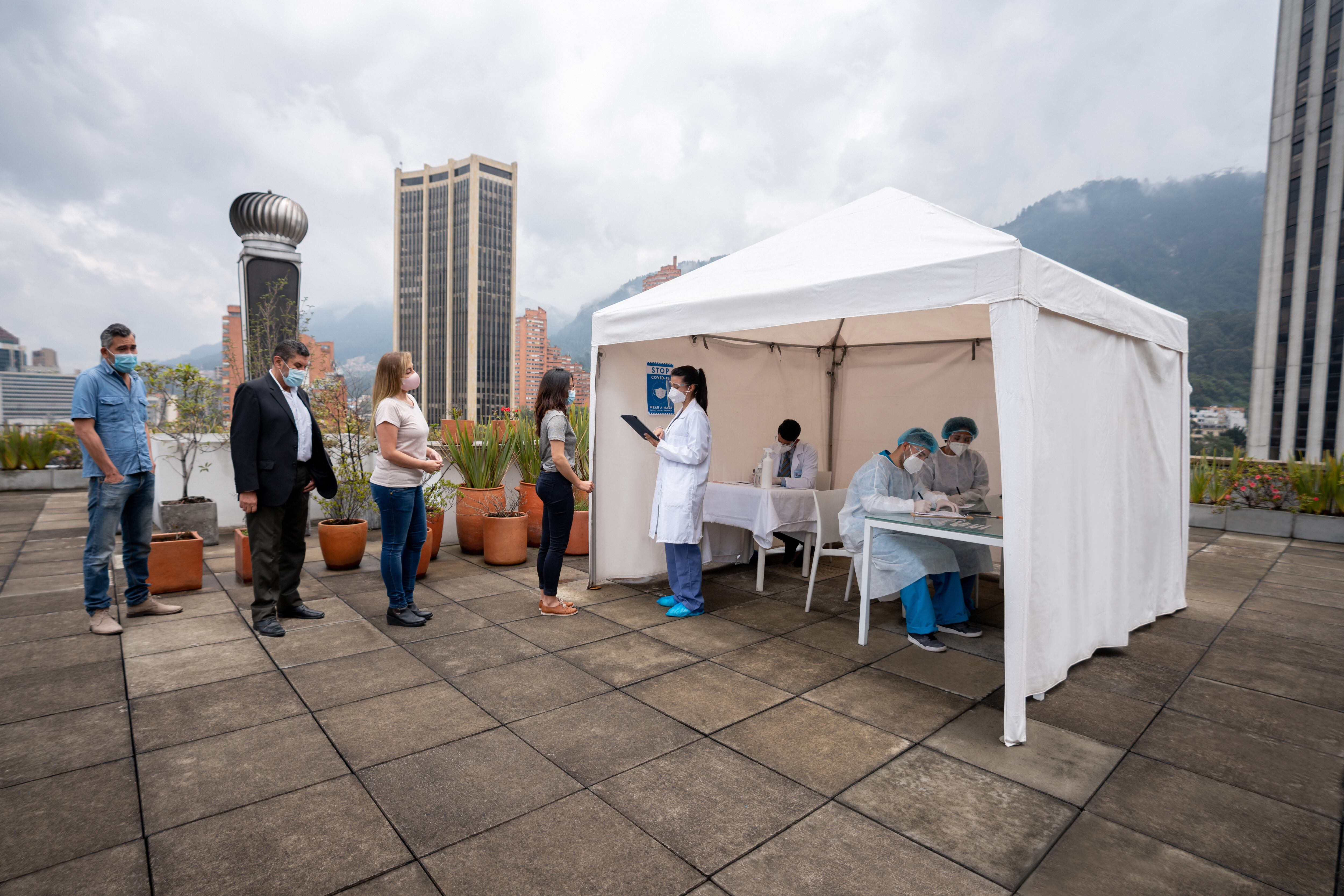 Group of Latin American people in line waiting to get their COVID-19 vaccine at a vaccination stand - immunization program concepts