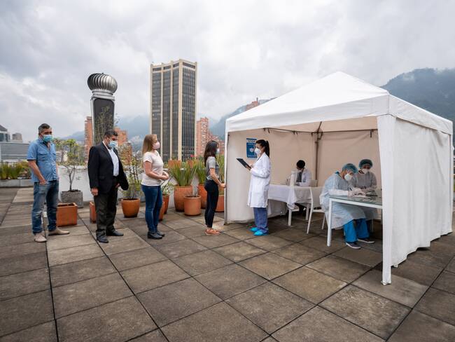 Group of Latin American people in line waiting to get their COVID-19 vaccine at a vaccination stand - immunization program concepts