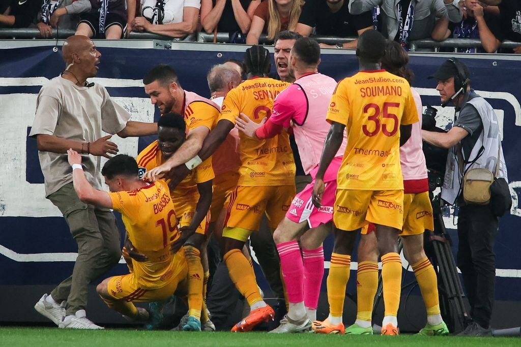 Momento en que los jugadores del  Rodez caen al suelo luego de que uno de ellos fue empujado por un hincha del Girondins Burdeos. Foto: Thibaud MORITZ / AFP) (Photo by THIBAUD MORITZ/AFP via Getty Images.
