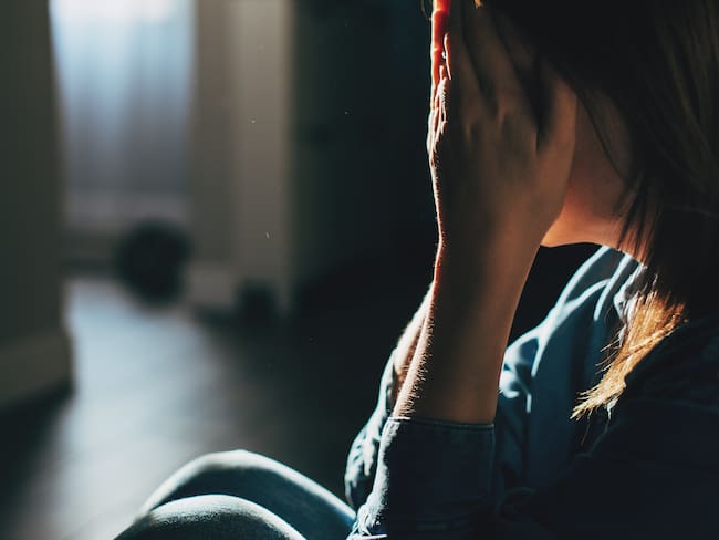 Silhouette of sad and depressed woman sitting on the floor at home