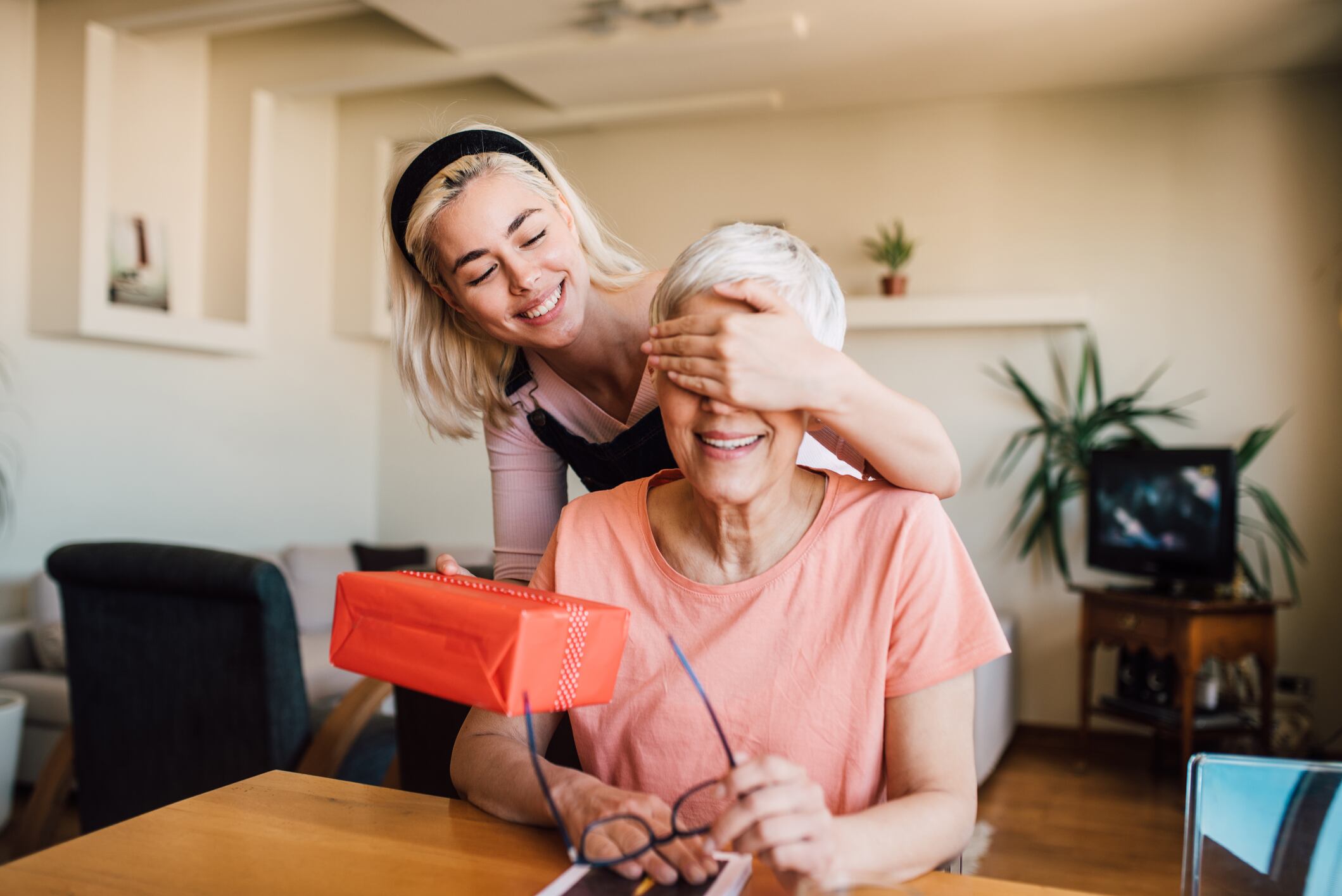 Older woman receiving a surprise from her happy daughter