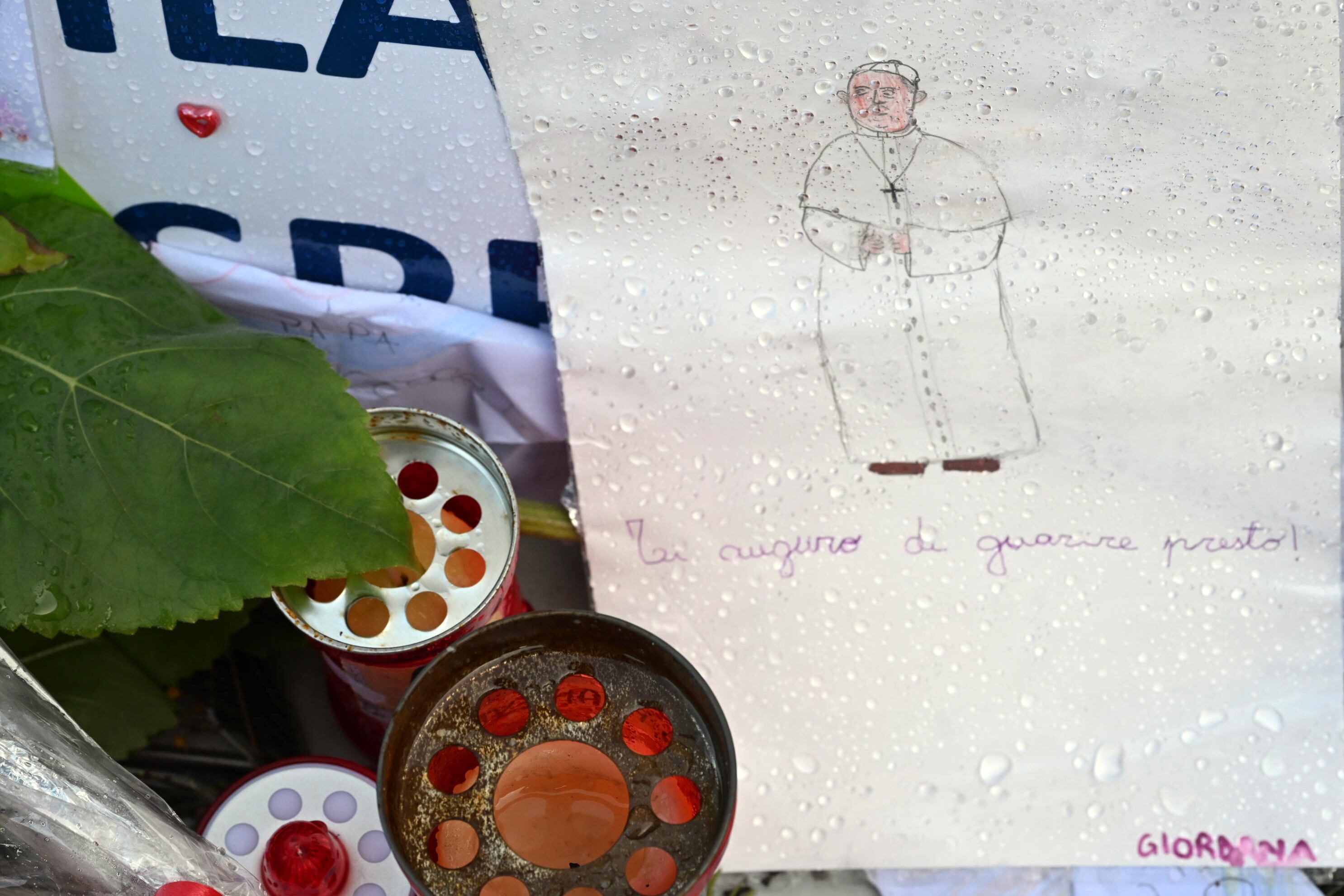 Roma (Italia), 26/02/2025.- Velas, dibujos y mensajes para el papa Francisco en la estatua del papa San Juan Pablo II frente al hospital universitario Gemelli, donde está hospitalizado el argentino.