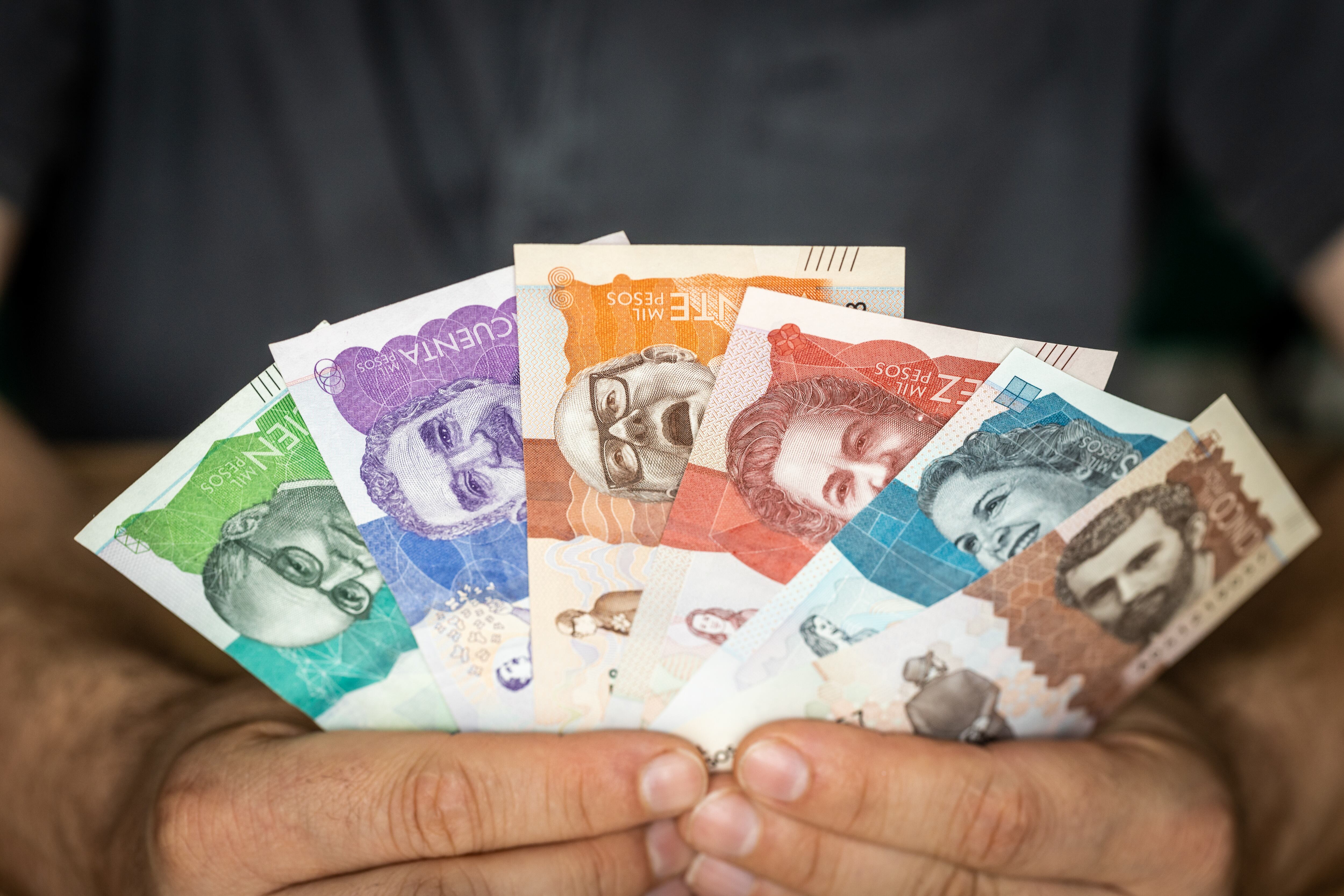 Hombre sosteniendo billetes colombianos de diferentes denominaciones (Getty Images)