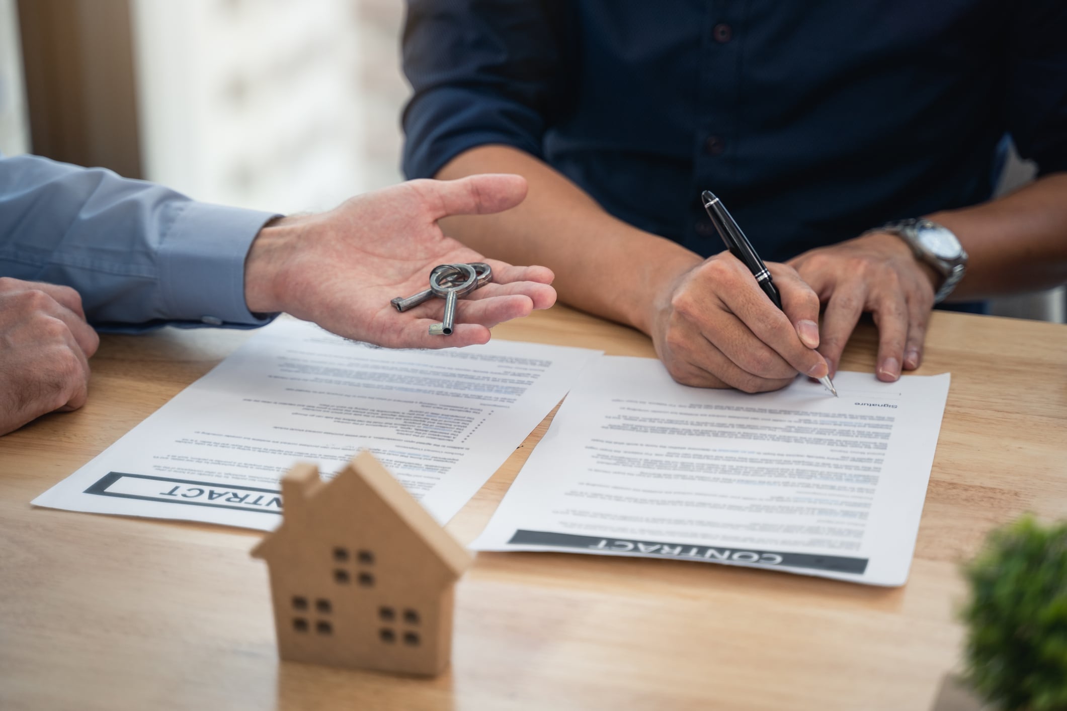 Dos personas firmando un contrato y entregando las llaves de la vivienda (Getty Images)